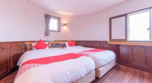a bedroom with two beds with red pillows at Tabist Hotel Sankoen in Hitachi