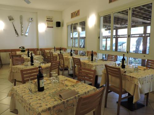 a restaurant with tables and chairs with wine bottles on them at Hotel Il Pino in San Vincenzo