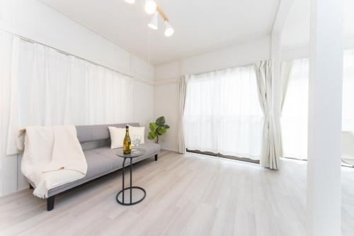 a white living room with a couch and a table at Miraie Yokkaichi Higashihino in Yokkaichi