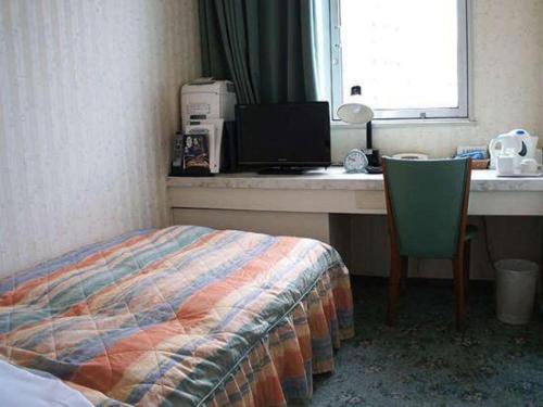 a bedroom with a bed and a desk with a computer at Hotel Abest Aomori in Aomori