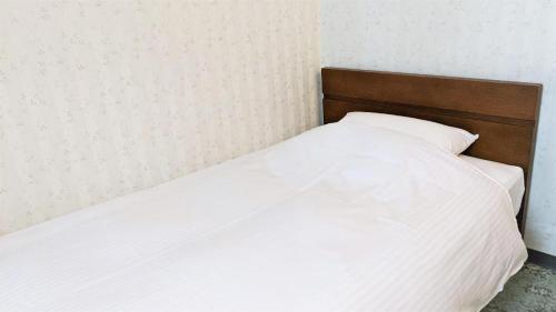 a bed with white sheets and a wooden headboard at Hotel Abest Aomori in Aomori