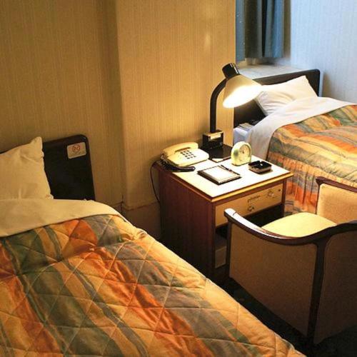 a hotel room with a bed and a desk with a lamp at Hotel Abest Aomori in Aomori