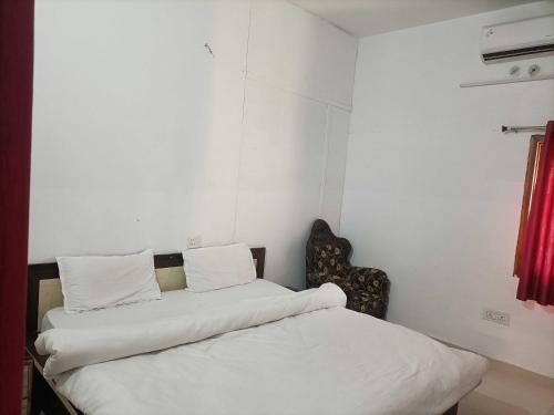a bedroom with a bed with white sheets and a chair at Hotel O by OYO Allahabad Property in Bhīta