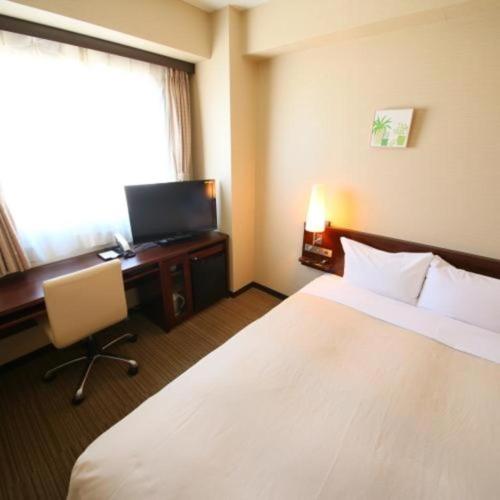 a hotel room with a bed and a desk and a television at Hotel Naito Kofu Showa in Kofu