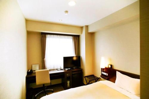 a bedroom with a bed and a desk and a window at Hotel Naito Kofu Showa in Kofu