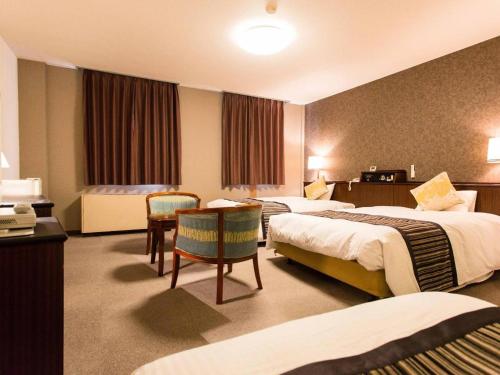 a hotel room with two beds and a table at Hotel AreaOne Miyazaki City in Beppuchō