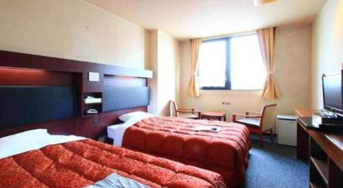 a hotel room with two beds and a television at Hotel Honjin in Kumamoto