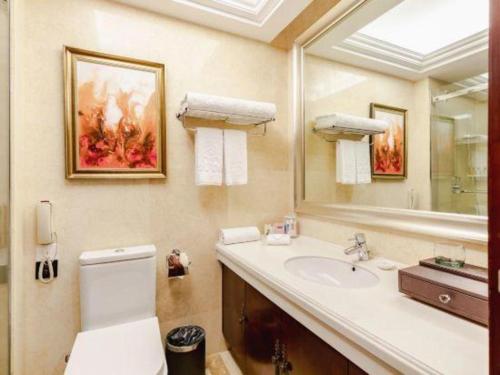 a bathroom with a sink and a mirror and a toilet at Royal Duke Cherrabah Hotel Zhongshan in Yagang