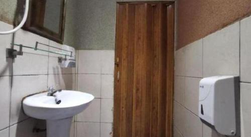 a bathroom with a sink and a wooden door at OYO 89780 Lodge 37 in Ranau