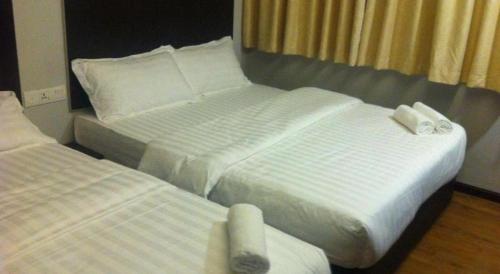 two beds in a hotel room with white sheets at Portview Hotel in Klang