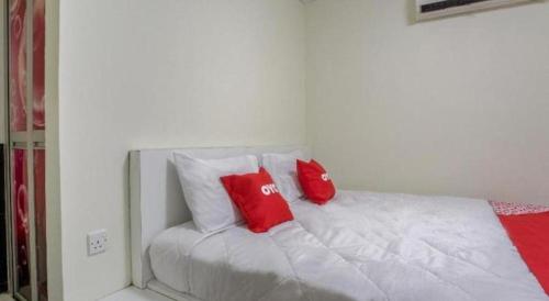 a white bed with two red pillows on it at OYO 822 Zande Motel Kuala Selangor in Kuala Selangor