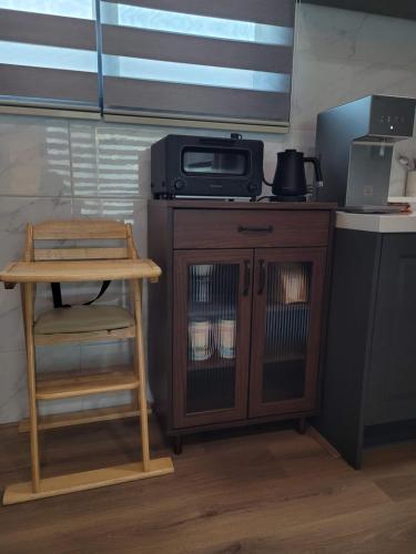a kitchen with a counter with a microwave and a stool at Joohane Jejudo House in Jeju