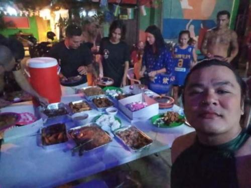 a group of people sitting around a table with food at mama hostel Bed & Breakfast in El Nido