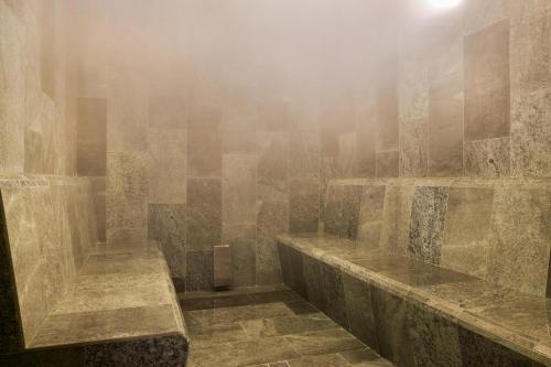 a misty bathroom with stone walls and benches at Hotel Riu Palace La Mola in Playa Migjorn