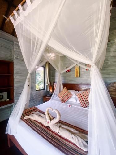 a bedroom with a bed with a canopy at Abian Huts Dream Beach Lembongan in Nusa Lembongan