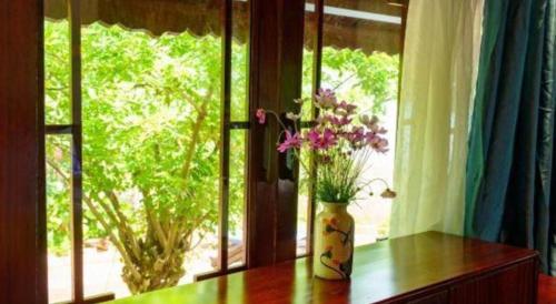 a vase of flowers sitting on a table near a window at Jun's Home in Buon Ma Thuot