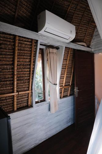 a room with a ceiling fan and a window at Abian Huts Dream Beach Lembongan in Nusa Lembongan