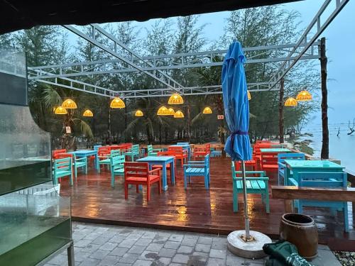 a group of tables and chairs with an umbrella at Dugong Bay - Làng Ẩm Thực & Sinh Thái - Eco & Seafood Village in Phu Quoc
