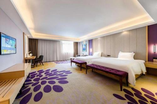 a large hotel room with two beds and a couch at Lavande Hotels· Guizhou Anshun Xi Railway Station in Anshun