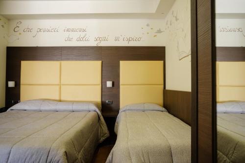 a bedroom with two beds and a sign on the wall at Hotel Ristorante Da Tonino in Recanati