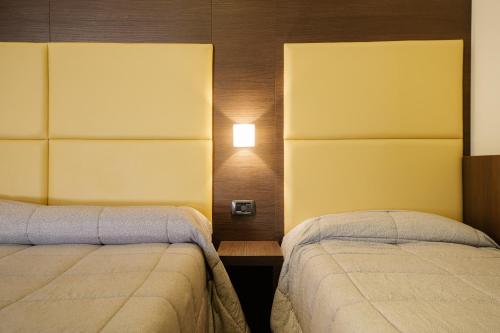 a bedroom with two beds and a light on the wall at Hotel Ristorante Da Tonino in Recanati