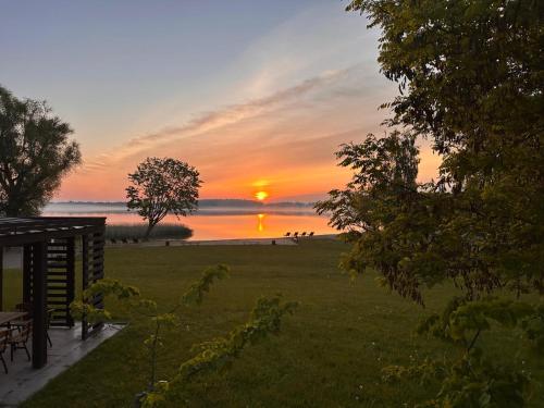 a sunset over the water with the sun in the distance at Świat Jezior in Mikołajki