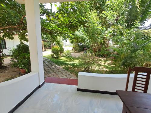 a porch with a table and a view of a garden at Holiday Beach Guesthouse in Kalkudah