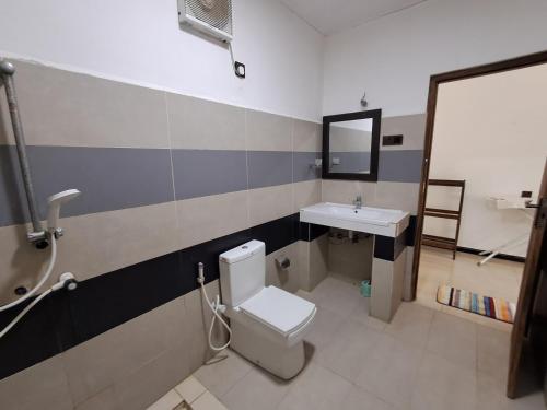 a bathroom with a toilet and a sink at Holiday Beach Guesthouse in Kalkudah