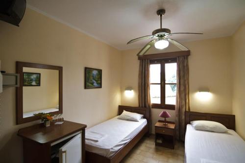 1 dormitorio con 2 camas y ventilador de techo en Mango Rooms, en Rodas