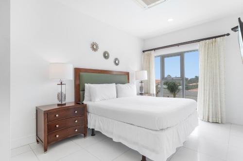 a white bedroom with a large bed and a window at Arubas Life 207 in Noord
