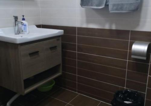a bathroom with a sink and brown tiles at Boxianyuan Three-Bedroom Apartment in Qinhuangdao
