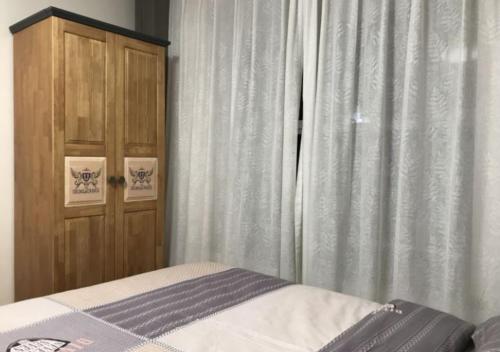 a bedroom with a bed and a wooden cabinet at Boxianyuan Three-Bedroom Apartment in Qinhuangdao