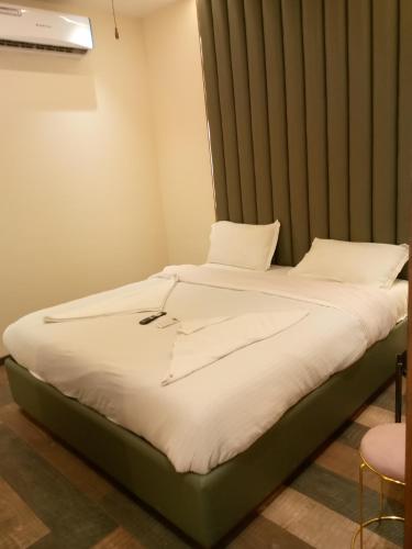a bed with white sheets and a headboard in a room at The Velvet Crown Residency in Bhiwandi