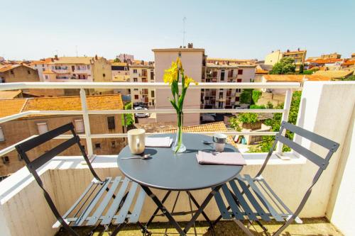 d'une table avec deux chaises et d'un vase avec des fleurs sur le balcon. dans l'établissement Zenitude Résidences - Studio privé - Balcon Clim Self-Checking Animaux Bienvenus, à Béziers