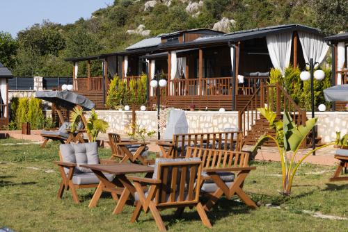 a group of picnic tables and chairs and a house at Kekova Garden Village in Demre