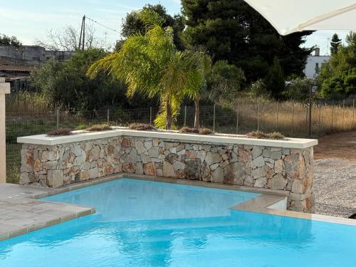 a swimming pool with a stone retaining wall at Abate Filippo apartment in Nardò