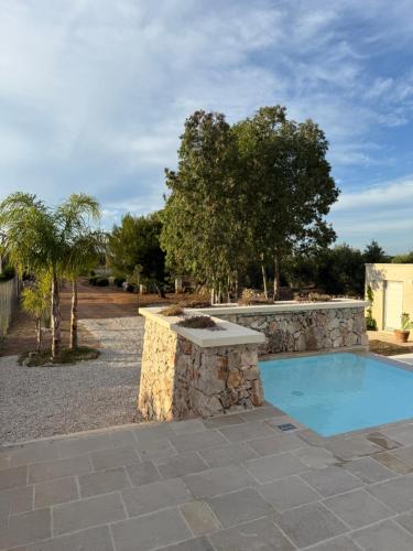 a stone retaining wall around a swimming pool with a stone bench at Abate Filippo apartment in Nardò