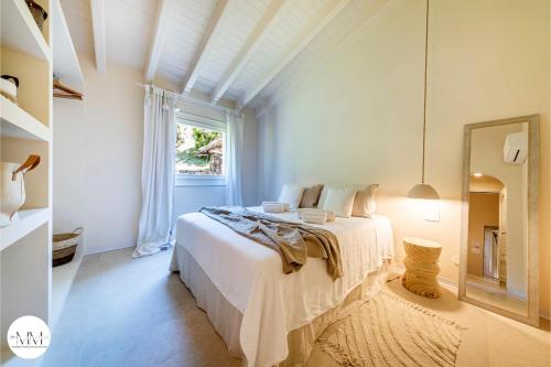 una camera da letto bianca con un letto e uno specchio di Porto Cervo Villa Sara a Porto Cervo