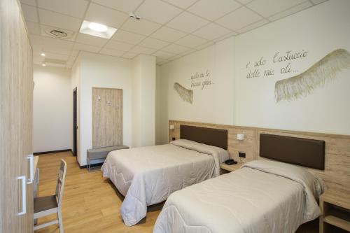 a room with two beds and a tv on the wall at Hotel Ristorante Da Tonino in Recanati
