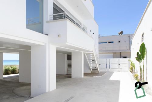 a white house with a staircase in front of a building at HOTIDAY Apartment Collection - Torre Lapillo in Porto Cesareo