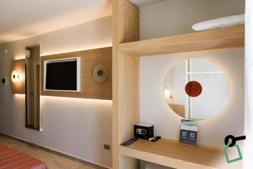 a room with a mirror and a tv on a wall at HOTIDAY Apartment Collection - Torre Lapillo in Porto Cesareo
