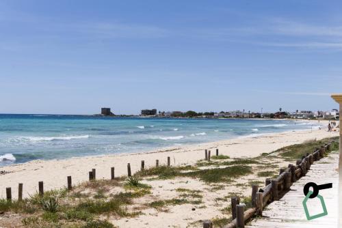 a beach with a fence and the ocean at HOTIDAY Apartment Collection - Torre Lapillo in Porto Cesareo