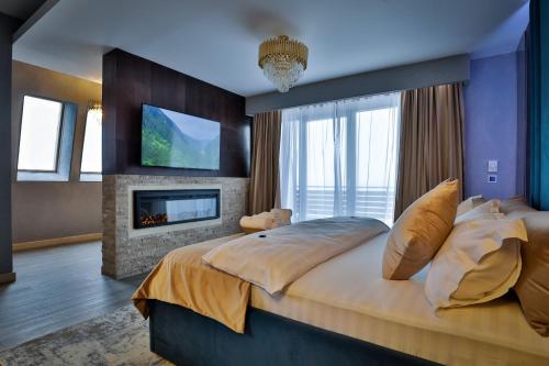 a bedroom with a large bed and a fireplace at Elexus Apartments Poiana Brasov in Poiana Brasov