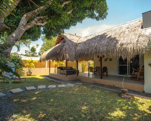 a house with a thatched roof and a yard at Halamanan Residences in Panglao