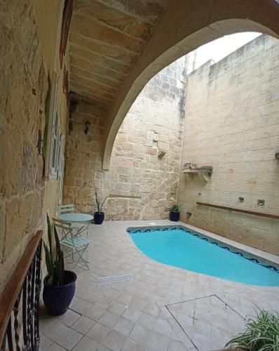 a swimming pool in a building with an arch over it at Gozobreak Farmhouses in Kerċem