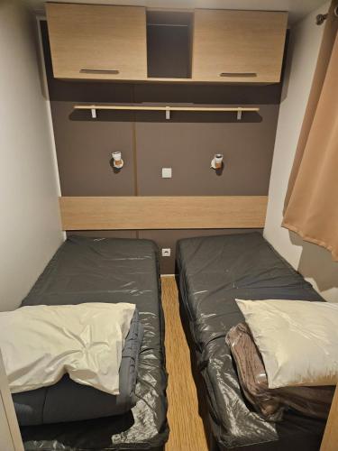 Cette petite chambre comprend 2 lits et une étagère. dans l'établissement mobil-home 6 personnes chez maylia, à Cadenet