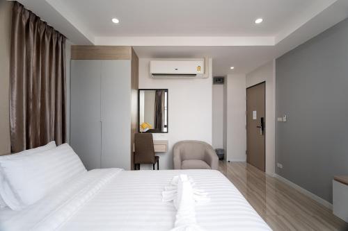 a bedroom with a white bed and a desk at The Riski Hotel at Bangphlat Station SHA in Bangkok
