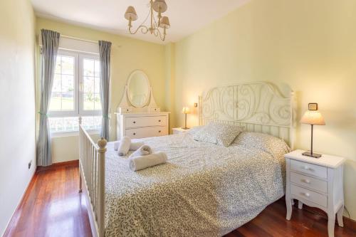 a bedroom with a white bed with a teddy bear on it at Tus vacaciones en Liencres in Liencres