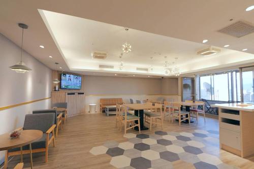 a restaurant with tables and chairs and a tv at Sky19 Hotel in Taipei