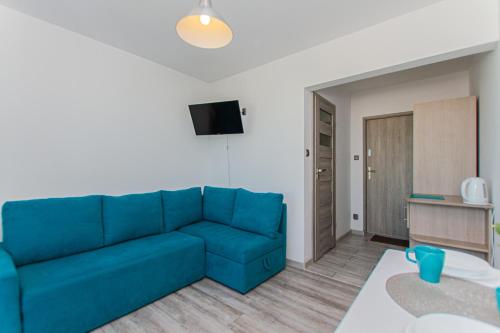 a living room with a blue couch and a table at Willa Aisza in Jastrzębia Góra